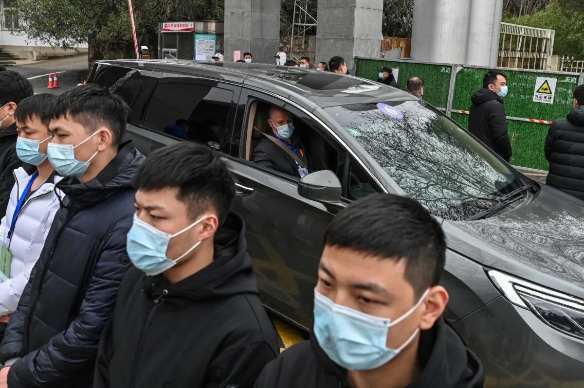 Members of the World Health Organization (WHO) team investigating the origins of the COVID-19, leave the Hubei provincial center for disease control and prevention, as a group of guards bar people from approaching, in Wuhan, China, on Feb. 1, 2021. (HECTOR RETAMAL/AFP via Getty Images)
