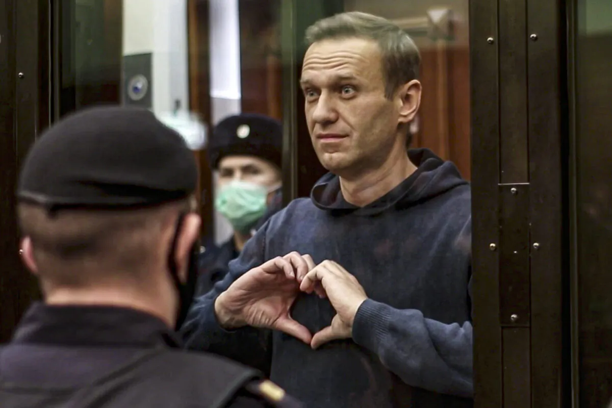 In this handout photo taken from a footage provided by Moscow City Court, Russian opposition leader Alexei Navalny shows a heart symbol standing in the cage during a hearing to a motion from the Russian prison service to convert the suspended sentence of Navalny from the 2014 criminal conviction into a real prison term in the Moscow City Court in Moscow, Russia, on Feb. 2, 2021. (Moscow City Court via AP)