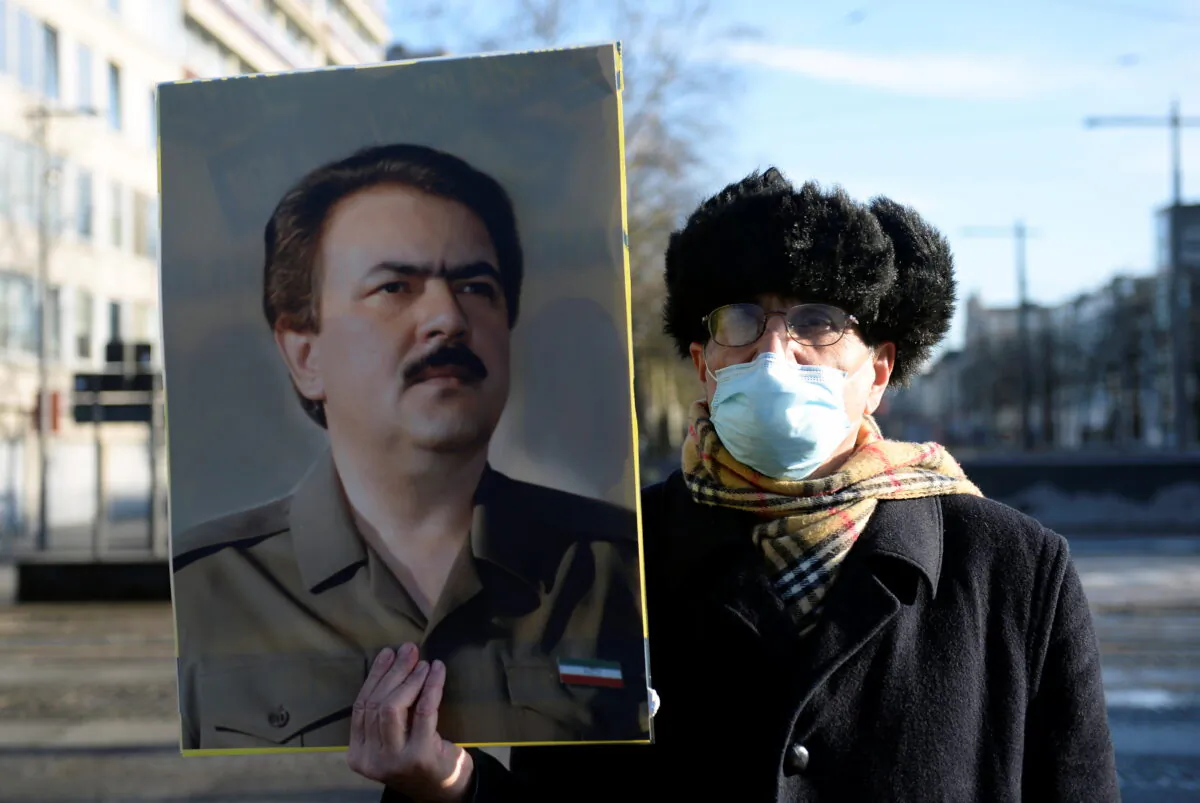 A man wearing a face mask holds a portrait of Iranian resistance leader Massoud Rajavi outside the court building in Antwerp, Belgium Feb. 4, 2021. (Johanna Geron/Reuters)