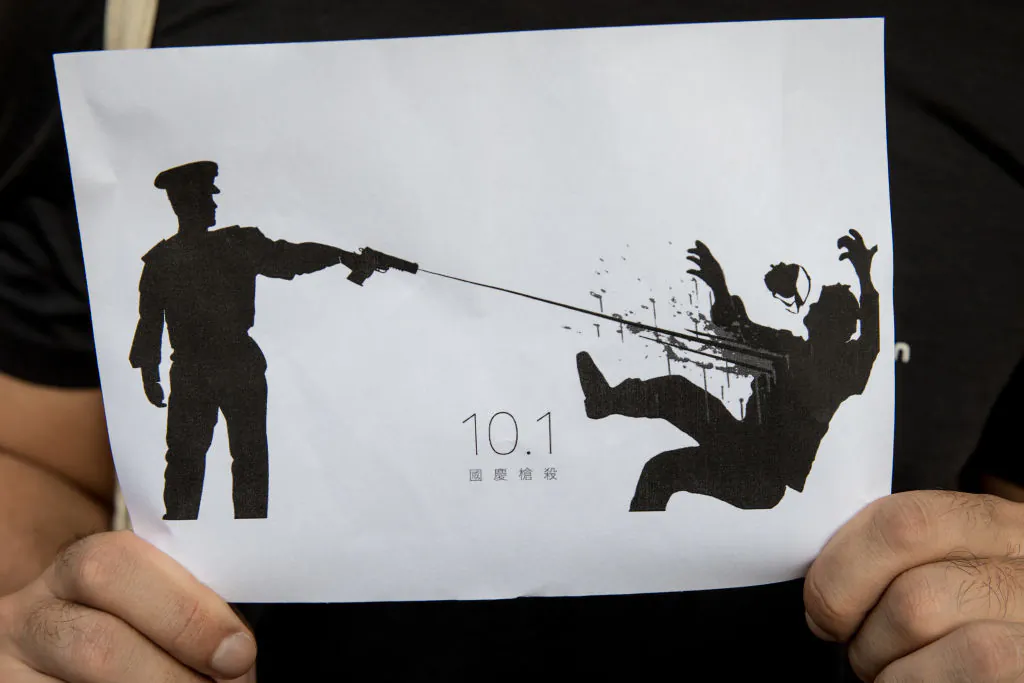 A man holds a sign depicting the shooting of a protester by a policeman during the Oct. 1 , 2019, protests in Hong Kong, China, on Oct. 2, 2019. (Chris McGrath/Getty Images)