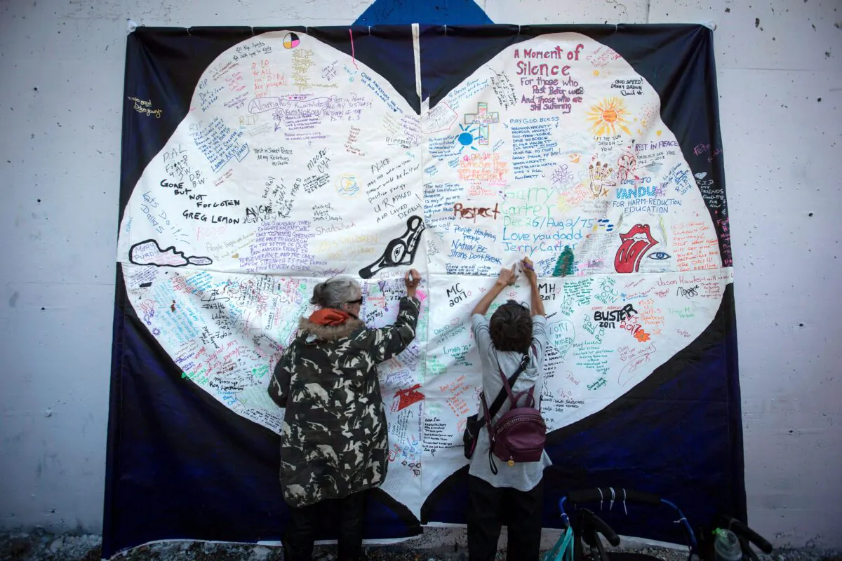 Women write messages on a banner during a memorial service to remember those who have died from drug overdoses in B.C., on International Overdose Awareness Day in Vancouver’s Downtown Eastside on Aug. 31, 2017. (The Canadian Press/Darryl Dyck)