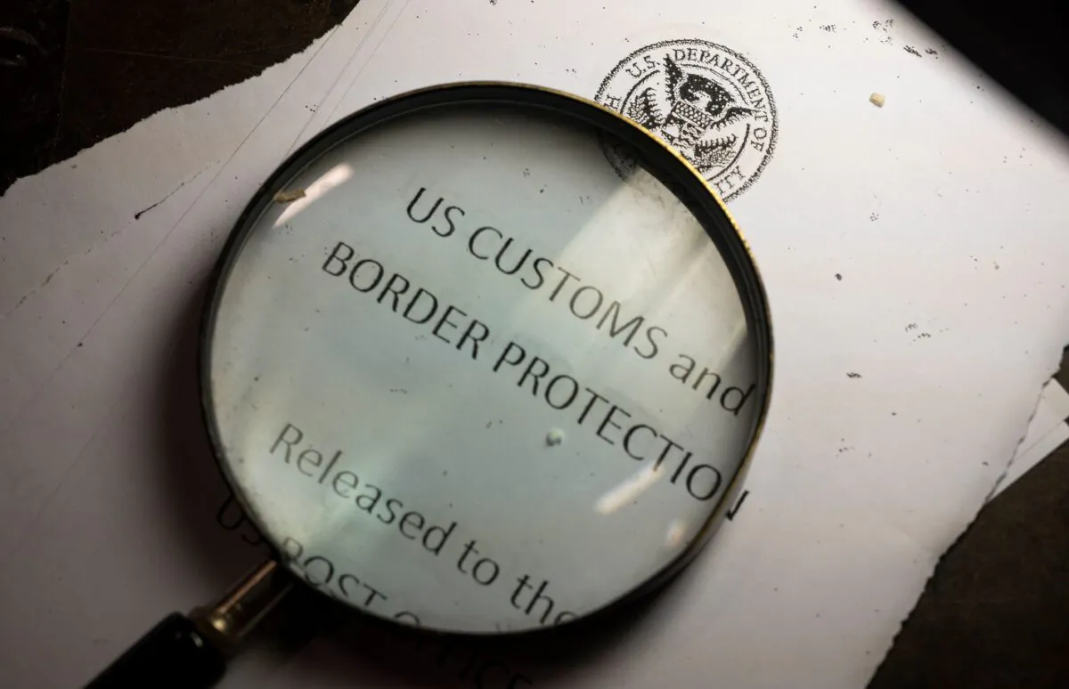 A magnifying glass is seen next to a logo of the Customs and Border Protection, Trade and Cargo Division at John F. Kennedy Airport's US Postal Service facility in New York on June 24, 2019. (Johannes Eisele/AFP via Getty Images)
