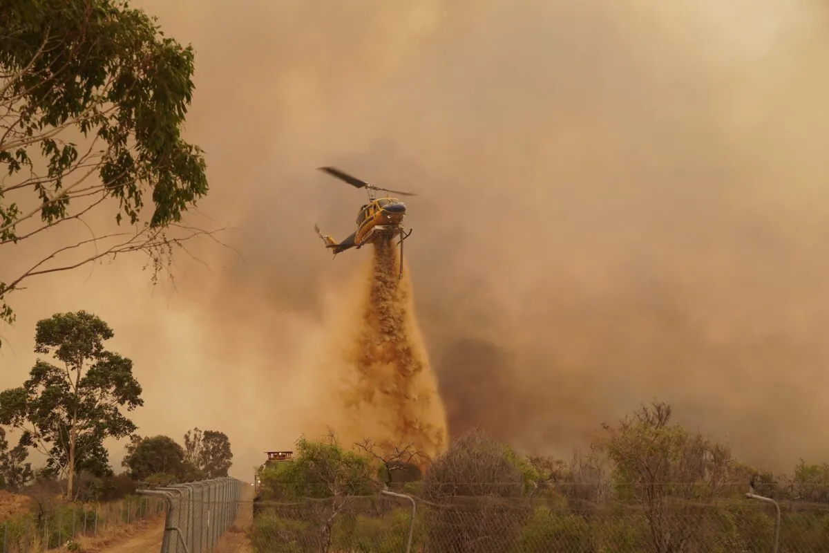 An aerial Firefighting helicopter drops fire retardant in an attempt to contain a bushfire in Wooroloo in Perth, Australia on Feb. 2, 2021. (Evan Collis/Department of Fire and Emergency Services via Getty Images)