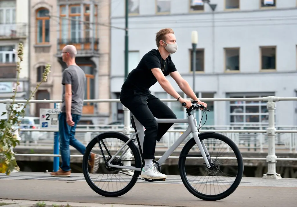 A Cowboy's employee, wearing a protective face mask, rides a Cowboy electric bike in the streets of Brussels, on July 28, 2020. (JOHN THYS/AFP via Getty Images)