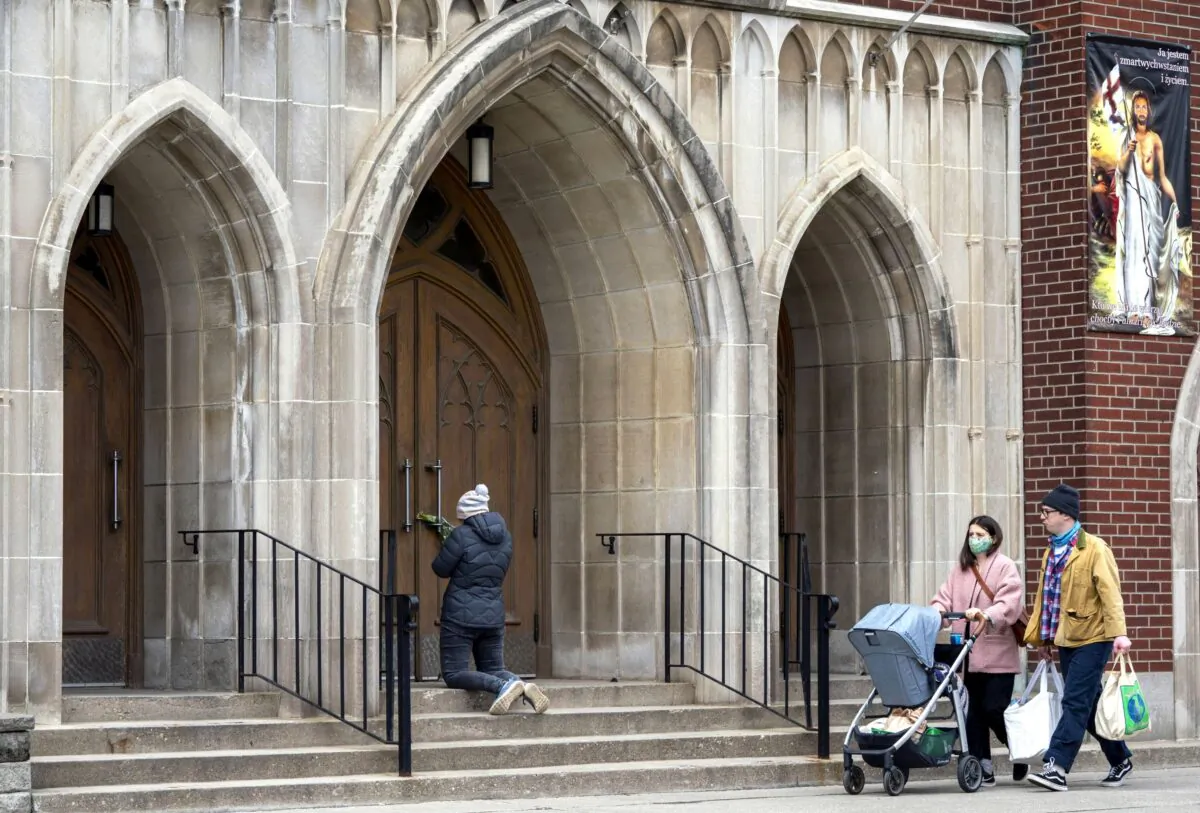 A woman prays on the steps outside St. Casimir Church in Toronto on May 1, 2020, during the COVID-19 lockdown. (The Canadian Press/Frank Gunn)