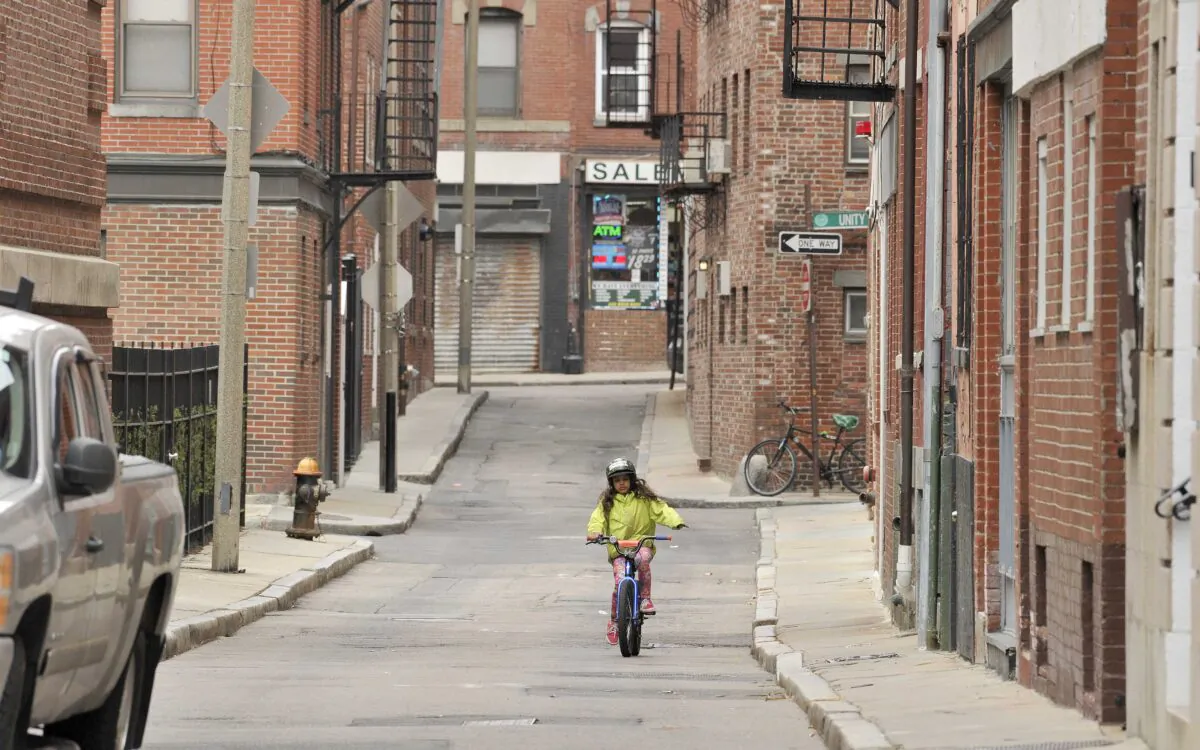 A young girl rides her bike on empty city streets with no school and a lack of tourist due to the coronavirus disease (COVID-19) in Boston, Mass., on March 12, 2020. (Joseph Prezioso/AFP via Getty Images)