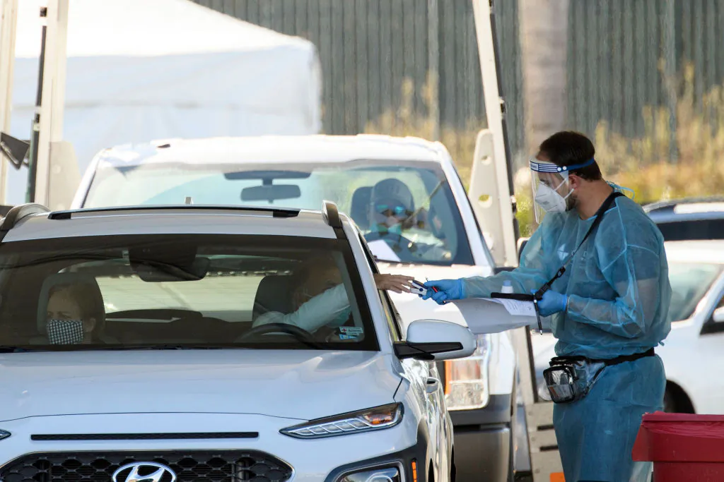 A COVID-19 testing site staff member uses a pulse oximeter to screen a driver at a drive-up testing site at the Orange County Fairgrounds in Costa Mesa, Calif., Nov. 17, 2020. (Patrick T. Fallon/AFP via Getty Images)