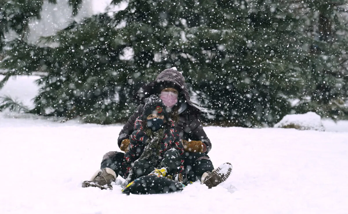A woman and child ride a snowboard down a small hill in downtown Brooklyn during a snowstorm in New York, Sunday, Feb. 7, 2021. (Kathy Willens/AP)
