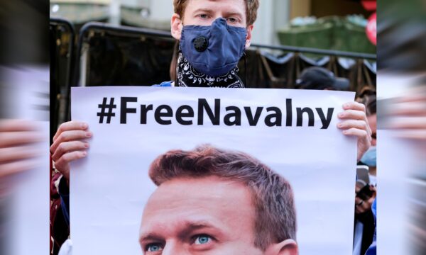 A protester wearing a face mask holds a poster of Alexei Navalny