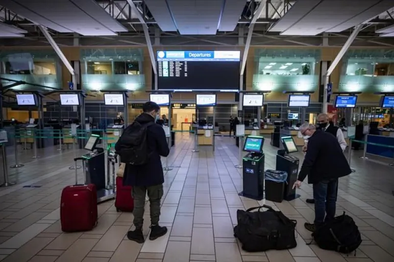 A WestJet employee assists a person checking in for a domestic flight at Vancouver International Airport on Jan. 21, 2021. (Darryl Dyck/The Canadian Press)