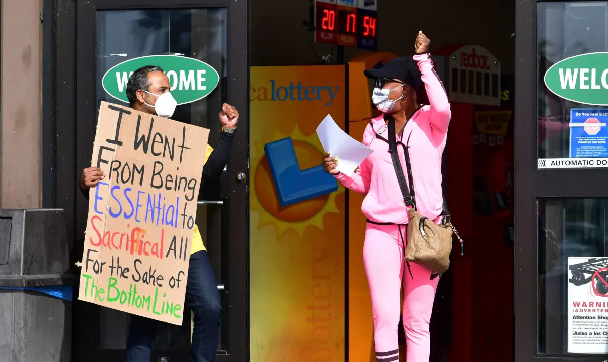 A woman gestures in support of supermarket workers holding placards in protest in front of a Food 4 Less supermarket in Long Beach, Calif., on Feb. 3, 2021. (Frederic J. Brown/AFP via Getty Images)