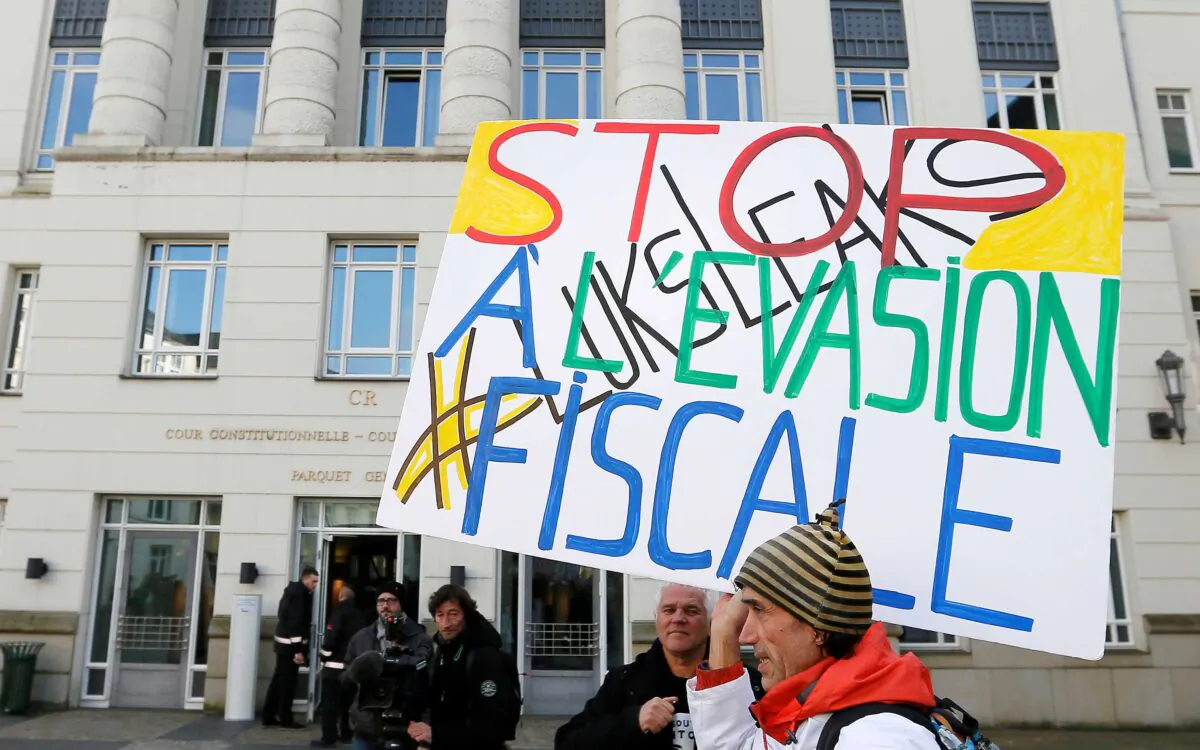 A man holds a placard reading “Stop tax avoidance” during a protest outside the courthouse ahead of the LuxLeaks trial before an appeal court in Luxembourg on Dec. 12, 2016. (Yves Herman/Reuters)