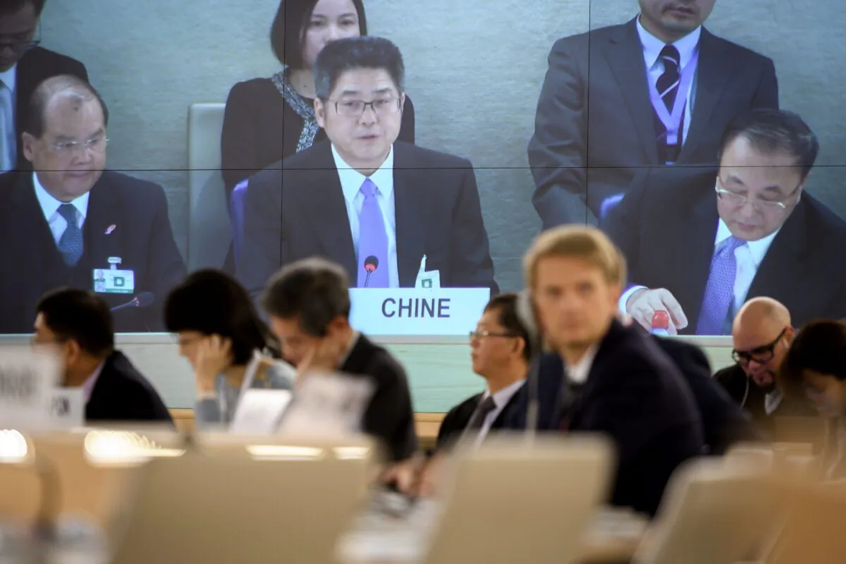 Chinese Vice Minister of Foreign Affairs Le Yucheng (C) is seen on a giant TV screen delivering a speech before the United Nations (UN) Human Rights Council in Geneva, on Nov. 6, 2018. (Fabrice Coffrini/AFP via Getty Images)