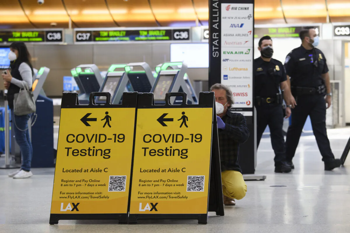 A traveler takes a photo of a COVID-19 testing sign at the Tom Bradley International Terminal, in Los Angeles, Calif., on Feb. 4, 2021. (Patrick T. Fallon/AFP via Getty Images)