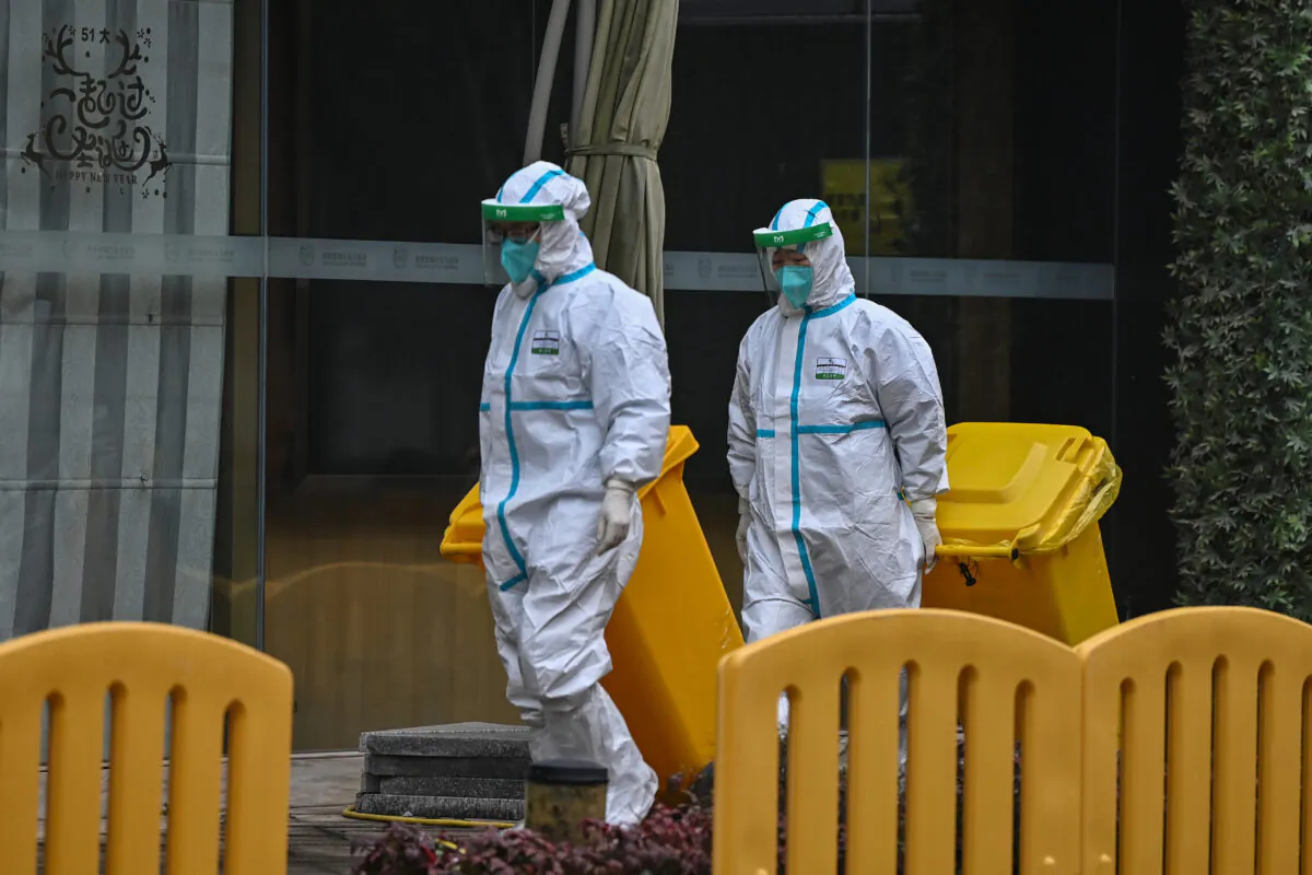 Workers wearing protective gear are seen in the compounds of The Jade Boutique Hotel, where members of the World Health Organization (WHO) team investigating the origins of the COVID-19 pandemic are due to complete their quarantine, in Wuhan, China, on Jan. 28, 2021. (Hector Retamal/AFP via Getty Images)