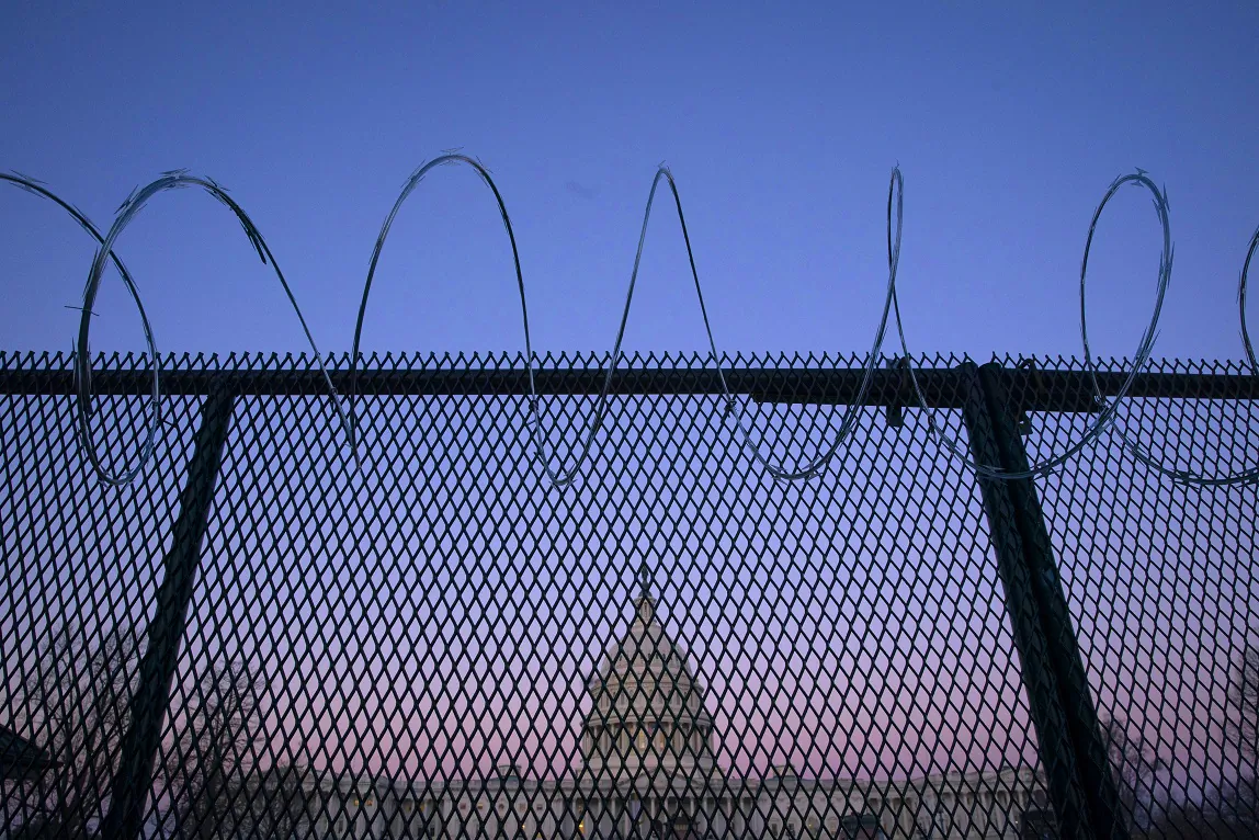 The U.S. Capitol building is seen through barbed wire fencing at sunrise in Washington on Feb. 8, 2021. (Sarah Silbiger/Getty Images)