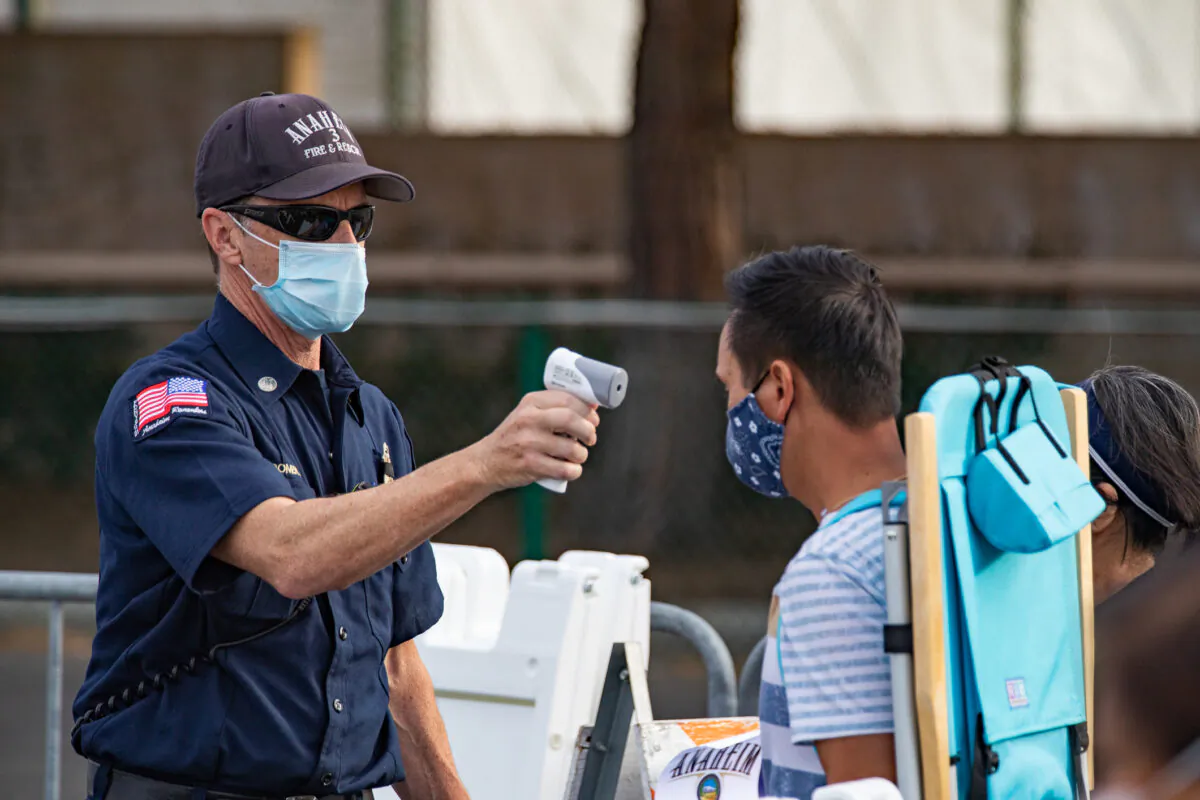 An Anaheim firefighter checks temperatures at a COVID-19 vaccination center set up in a parking area of Disneyland themepark in Anaheim, Calif., on Jan, 13, 2021. (John Fredricks/The Epoch Times)