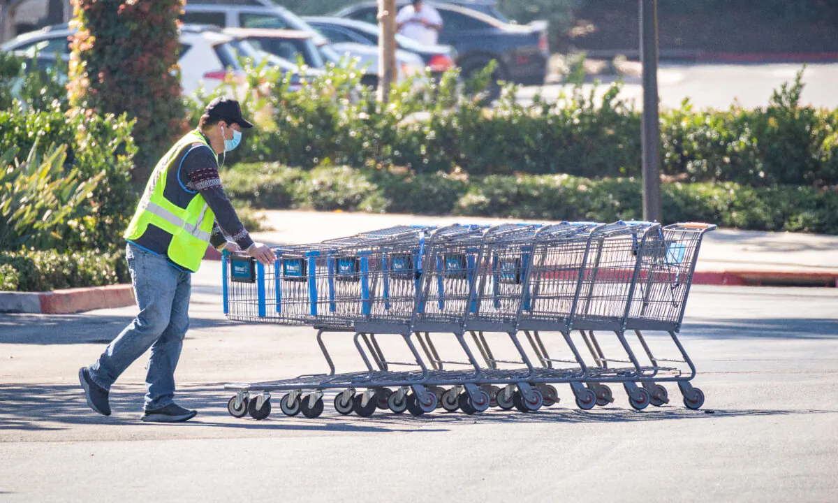 A worker pushes shopping carts in a Walmart parking lot in Irvine, Calif., on Feb. 5, 2021. (John Fredricks/The Epoch Times)