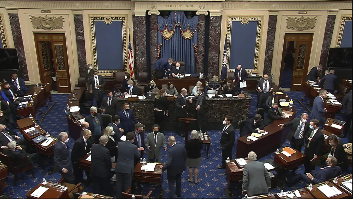 Senators gather around Senate Majority Leader Chuck Schumer (D-N.Y.) amid confusion about a request to strike comments from the record, in Washington on Feb. 10, 2021. (Senate Television via AP)