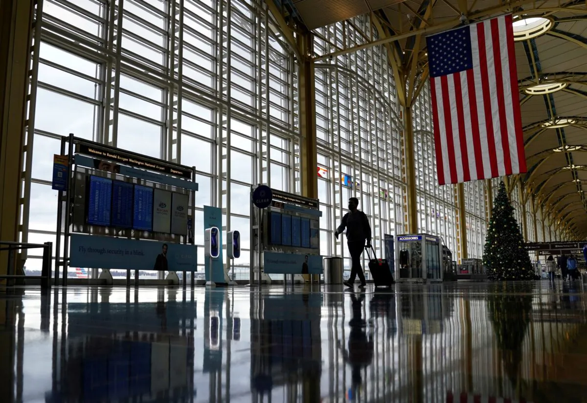A traveler walks past a Christmas tree as he makes his way through the Ronald Reagan Washington National Airport, in Arlington, Virginia, on Dec. 22, 2020. (Kevin Lamarque/Reuters File Photo)