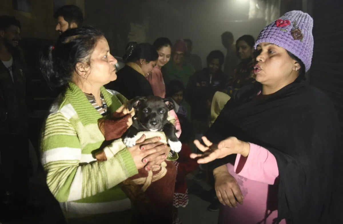 Residents—one holding a puppy—speak on a street in Amritsar after leaving their homes as tremors shook the city in Punjab State north-western India following a powerful earthquake in Tajikistan of a magnitude of 5.9 according to the United States Geological Survey (USGS), late Feb. 12, 2021. (Narinder Nanu/AFP via Getty Images)