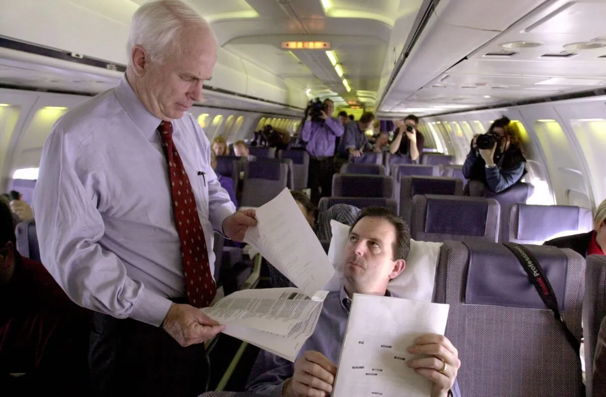 Late Arizona Senator John McCain (L) looks over some documents with campaign advisor John Weaver (R) while flying from Virginia Beach to Bismarck, North Dakota 28 February, 2000. (Roberto Schmidt/AFP via Getty Images)