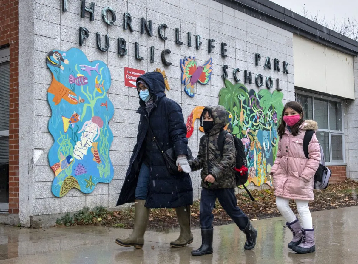A family walks past Thorncliffe Park Public School in Toronto on Dec. 4, 2020. (The Canadian Press/Frank Gunn)