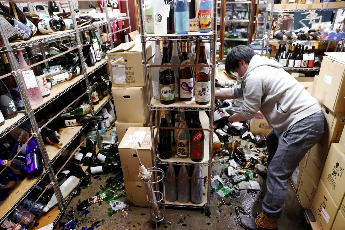 A liquor shop's manager clears the damaged bottles following an earthquake in Fukushima, northeastern Japan, on Feb. 13, 2021. (Jun Hirata/Kyodo News via AP)
