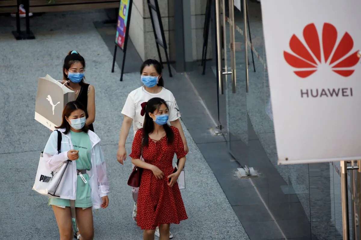 Women walk past a Huawei store at a shopping complex in Beijing on July 14, 2020. (Tingshu Wang/Reuters)