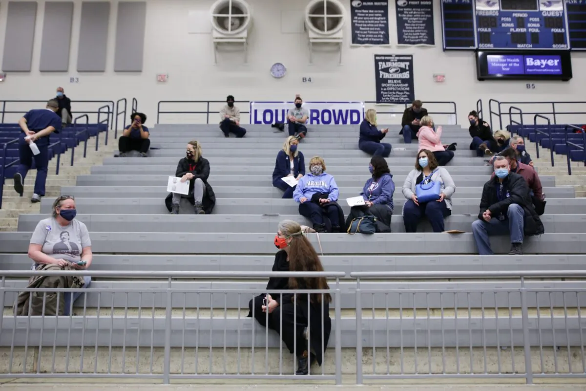 Educational staff at Kettering City Schools sit in bleachers after receiving their COVID-19 vaccine in Dayton, Ohio, on Feb. 10, 2021. (Megan Jelinger/AFP via Getty Images)