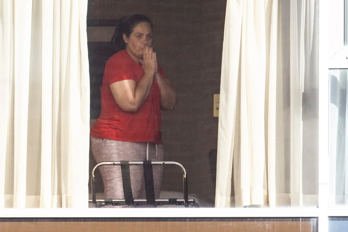 A woman gestures from her window towards reporters outside the Radison Blu hotel after arriving at Heathrow airport, and now quarantining, in London, on Feb. 15, 2021. (Dan Kitwood/Getty Images)