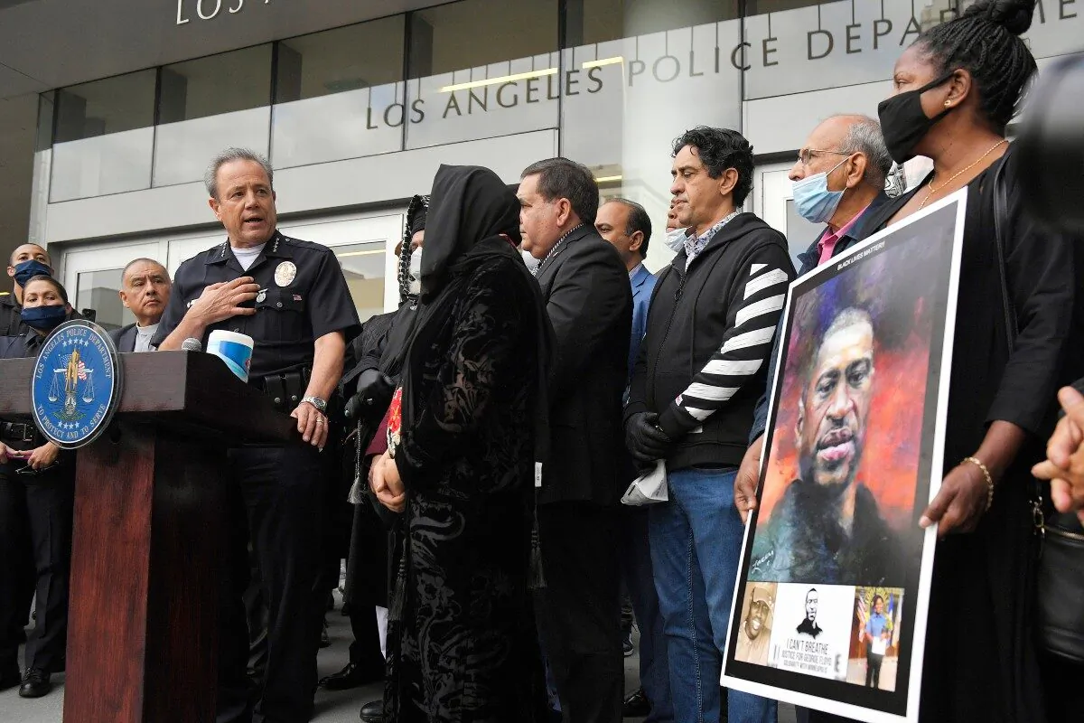 Los Angeles police chief Michel Moore (L) speaks as someone holds up a portrait of George Floyd during a vigil with members of professional associations and the interfaith community at Los Angeles Police Department headquarters in Los Angeles, Calif., on June 5, 2020. (Mark J. Terrill/ File/AP Photo)