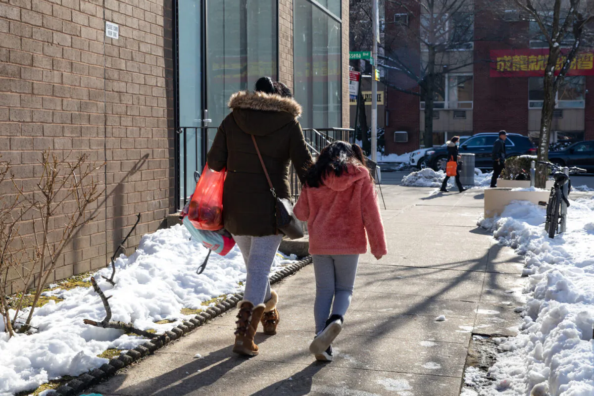 A woman and a little girl walk on the street in Flushing, New York on Feb. 10, 2021. (Chung I Ho/The Epoch Times)