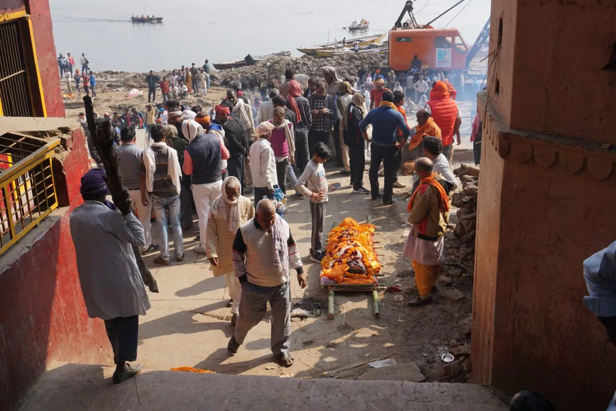 A corpse decked in marigold flowers waits for its turn on the pyre on the ground at the Manikarnika Ghat in Kashi on Feb. 12, 2021. (Venus Upadhayaya/Epoch Times)