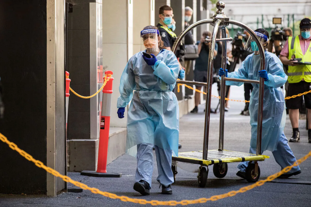 Workers assist people leaving the Holiday Inn in Melbourne, Australia on Feb. 16, 2021. (Darrian Traynor/Getty Images)