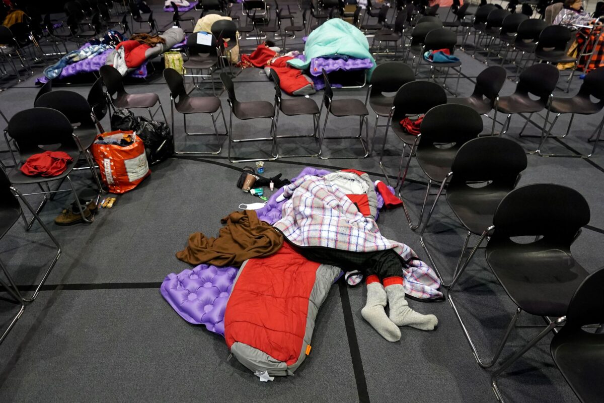 People seeking shelter from below freezing temperatures rest inside a church warming center Tuesday, Feb. 16, 2021, in Houston.