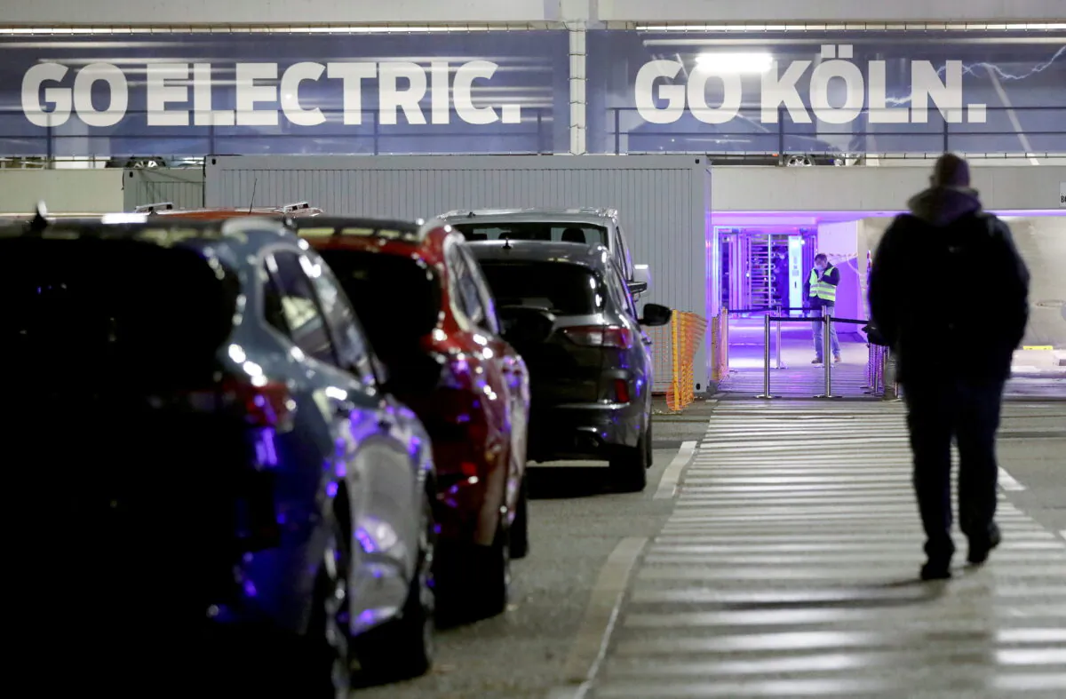 An employee of the Ford Motor Company makes his way to work following the company's announcement to build future electric cars in Cologne, Germany, on Feb. 17, 2021. (Oliver Berg/Pool via Reuters)
