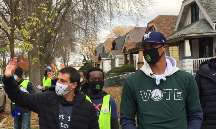 Milwaukee Bucks Senior Vice President Alex Lasry (L) and then-Bucks guard George Hill walk through a neighborhood in Milwaukee, Wis., on Oct. 24, 2020. (AP Photo/Steve Megargee File)