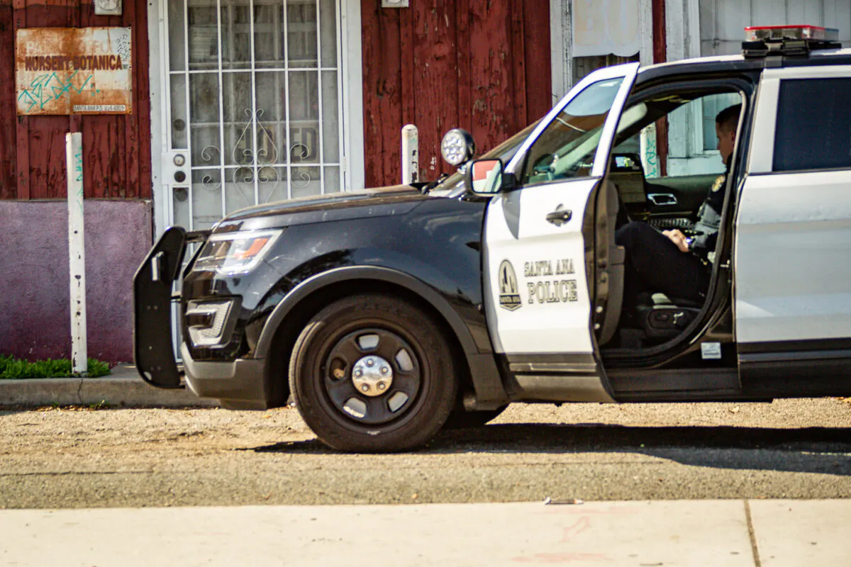A police officer sits in his vehicle near the scene of a fatal shooting in Santa Ana, Calif., on Feb. 17, 2021. (John Fredricks/The Epoch Times)
