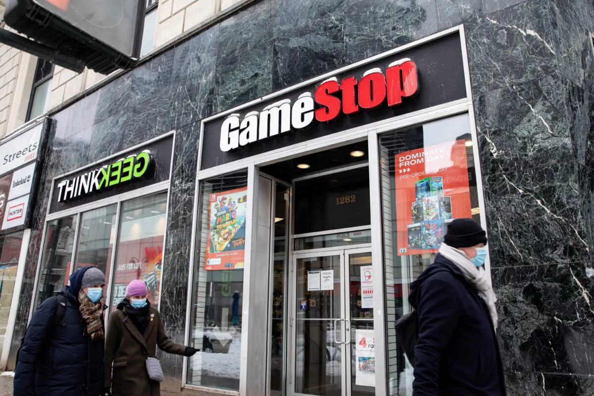 People wearing protective face masks walk past a GameStop store in New York on Feb. 2, 2021. (Chung I Ho/The Epoch Times)