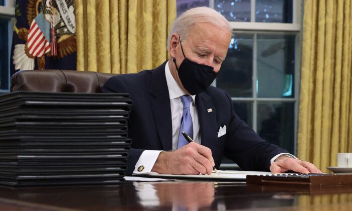 President Joe Biden signs a series of executive orders at the Resolute Desk in the Oval Office just hours after his inauguration in Washington on Jan. 20, 2021. (Chip Somodevilla/Getty Images)