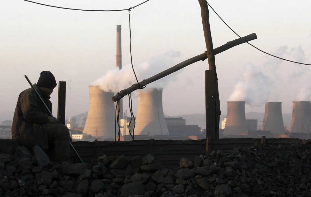 A miner sits near the Sunjiawan Coal Mine accident site in Fuxin, northeast China’s Liaoning Province, China on Feb. 18, 2005. (China Photos/Getty Images)
