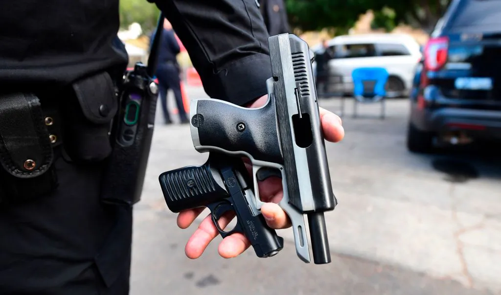 A Los Angeles Police Department officer displays recovered guns from residents turning in firearms at a "Gun Buy Back" event taking place in three locations across Los Angeles on Dec. 5, 2020. (Frederic J. Brown/AFP via Getty Images)