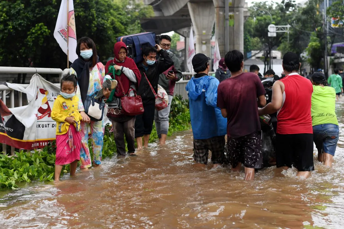 People walk through the water in an area affected by floods following heavy rains in Jakarta, Indonesia, on Feb. 20, 2021. (Aprillio Akbar/Antara Foto via Reuters)