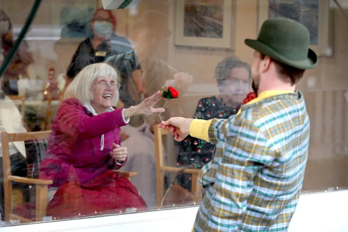 Award winning 'masters of the absurd' Dan Lees and Neil Frost of Mad Etiquette perform through the front window glass for residents at the Spring Lane Nursing Home in London, England, on Dec. 18, 2020. (Chris Jackson/Getty Images)