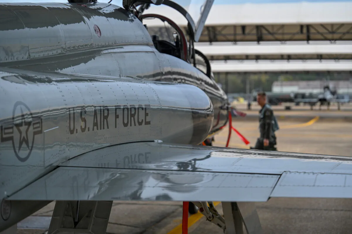 A U.S. Air Force pilot walks in front of a T-38 Talon at  Columbus Air Force Base, Miss., on Nov. 11, 2020. The T-38 is a two-seat trainer jet used by student pilots selected for the fighter track in pilot training. (U.S. Air Force photo by Airman 1st Class Davis Donaldson)