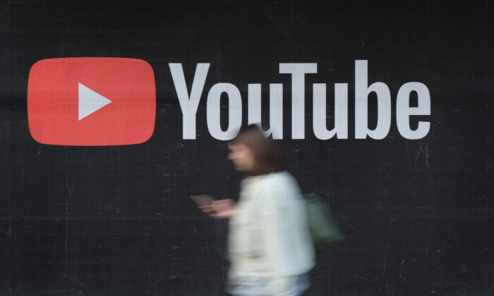 A woman with a smartphone walks past a billboard advertisement for YouTube in Berlin on Sept. 27, 2019. (Sean Gallup/Getty Images)