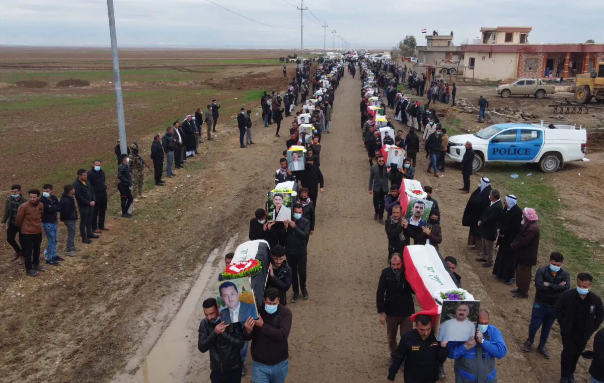 Mourners carry coffins wrapped in the Iraqi flag in a procession during a mass funeral for Yazidi victims of ISIS in the village of Kojo in the Sinjar district of Iraq, on Feb. 6, 2021. (Zaid Al-Obeidi/AFP via Getty Images)