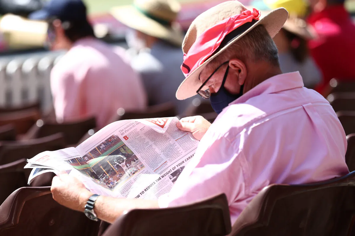 A spectator looks at a newspaper photograph of Steve Smith of Australia on Jane McGrath Day during day three of the 3rd Test match in the series between Australia and India at Sydney Cricket Ground in Sydney, Australia on Jan. 9, 2021. (Ryan Pierse/Getty Images)