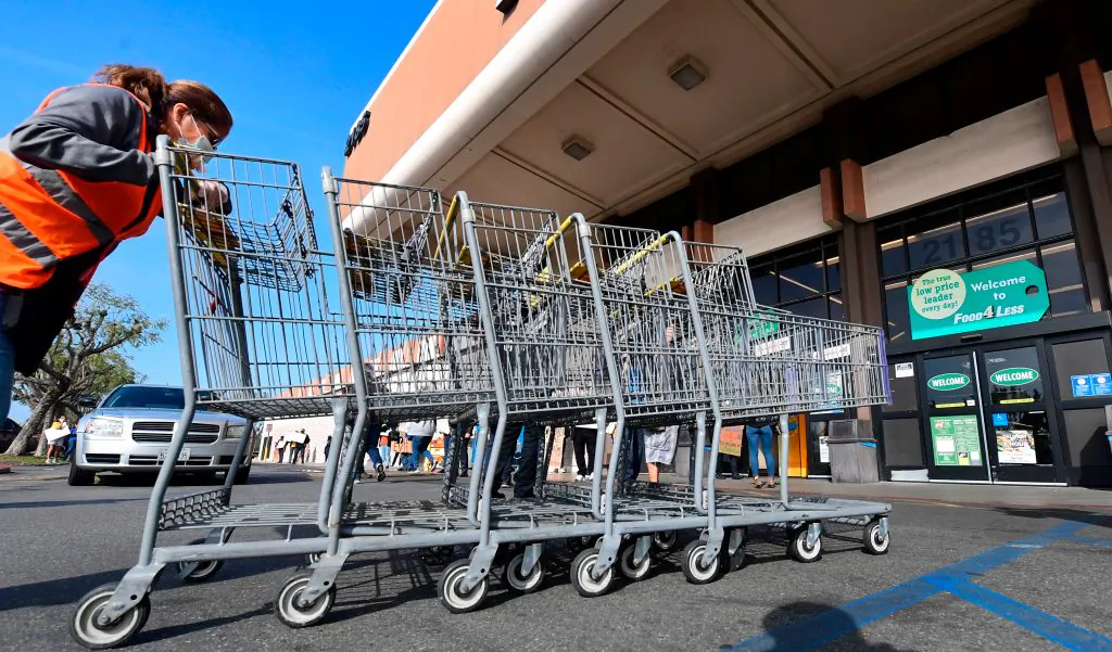 A Food 4 Less employee pushes carts past supermarket workers gathered to protest in front of the supermarket in Long Beach, California on February 3, 2021, after a decision by owner Kroger to close two supermarkets rather than pay workers an additional $4 in "hazard pay" for their continued work during the coronavirus pandemic. (Frederic J. Brown/AFP via Getty Images)